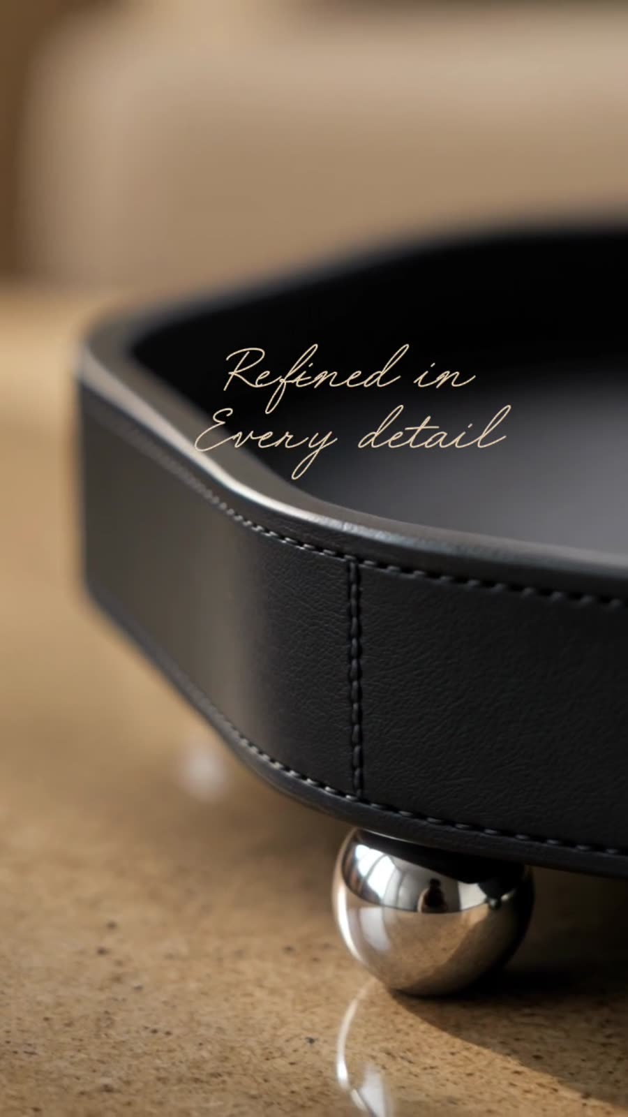Macro frame — stitched black leather tray on a polished metal ball foot